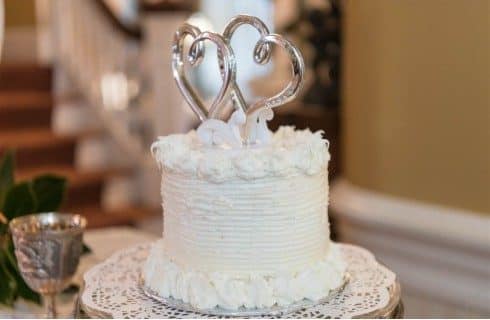 A small white wedding cake with two hearts as the topper