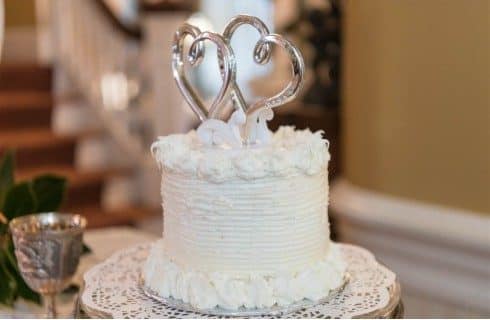 A small white wedding cake with two hearts as the topper