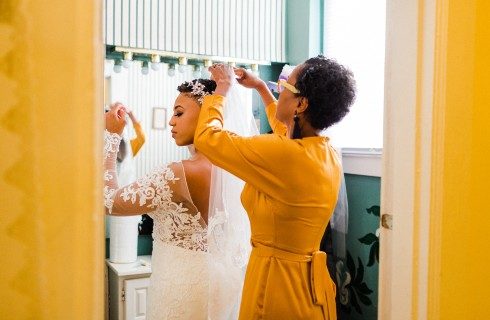 A woman in a yellow dress helping a ride get ready in a brightly lit room